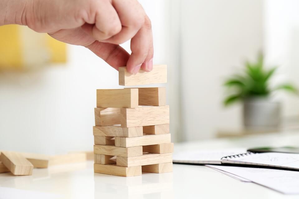 Image of a person stacking wooden blocks, representing how an experienced hospitality attorneys can guide you on the importance of evaluating various hospitality business structures before choosing one for your business.