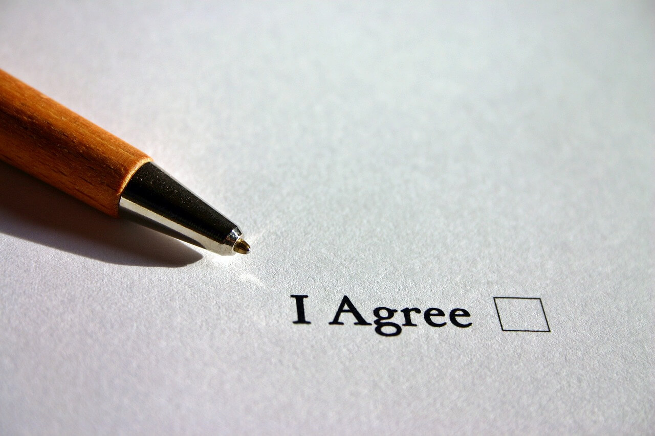 An image of a pen and a checkbox that reads ”I agree,” representing the risks for employers and others who enter into agreements that do not comply with the WV workers’ compensation fee schedule and how experienced workers’ compensation attorneys like Steven K. Wellman at Jenkins Fenstermaker, PLLC can help employers and insurers navigate WV workers’ compensation law.