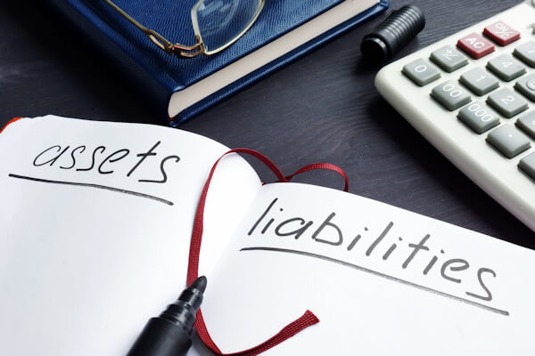 Image of a notebook listing “assets” and “liabilities,” representing how at Jenkins Fenstermaker, PLLC helps business clients navigate alternative business valuation approaches and which is best for their circumstances.