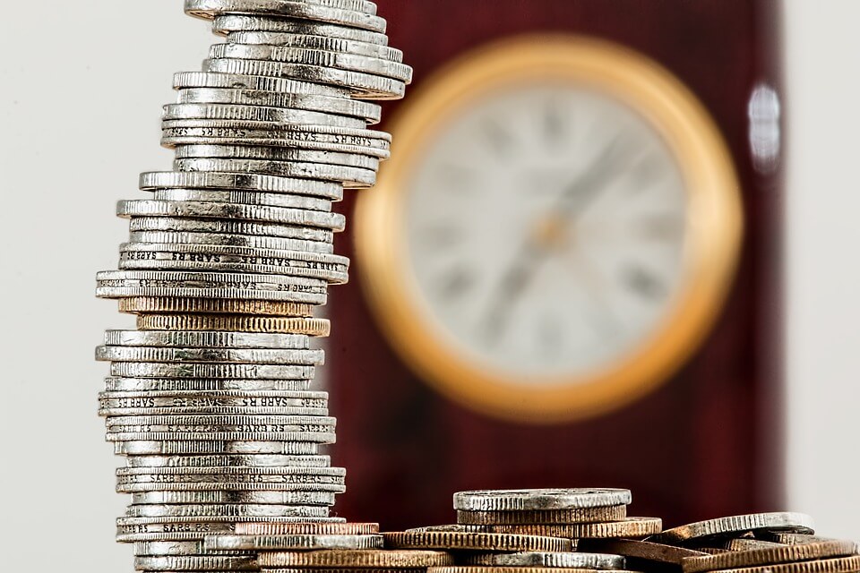 Image of coins with a clock in the background, representing the amendments to WV laws eliminating wage payment bonds in WV.