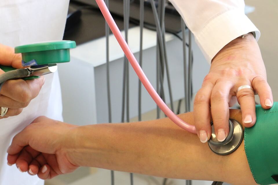 Image of a doctor checking a patient's blood pressure, representing ongoing discussions about limiting medical monitoring damages in WV.