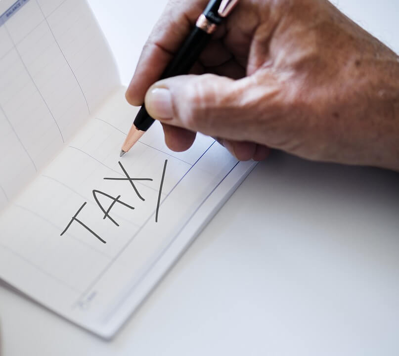 An image of a man writing the word “tax,” representing the need to use estate tax planning techniques to ensure your transfer of wealth after death is maximized.