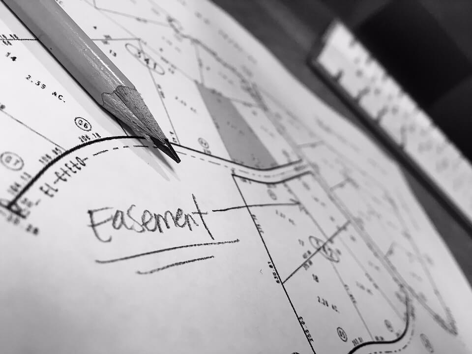 Image of property lines on paper with the word “easement,” representing the potential for commercial real estate disputes in WV and how a WV commercial real estate attorney at Jenkins Fenstermaker PLLC can help.