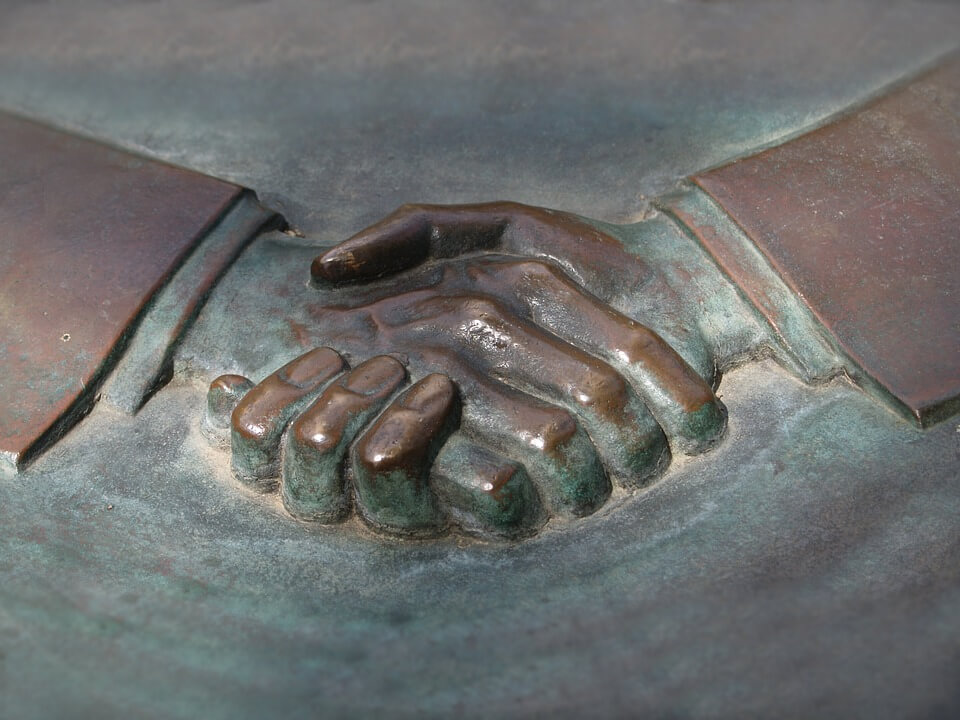 An image of a relief sculpture of hands shaking, representing the permanent nature of a business deal and how a WV mergers and acquisitions lawyer from Jenkins Fenstermaker can help you avoid mistakes.