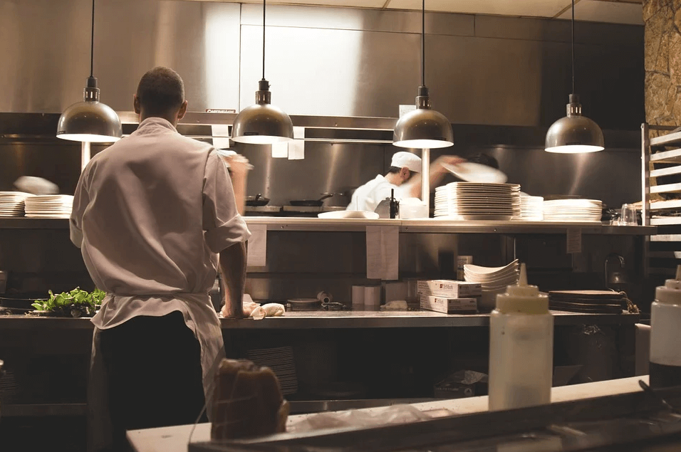 Image of cooks working in a restaurant kitchen, representing at Jenkins Fenstermaker, PLLC can answer your restaurant sale questions and facilitate restaurant M&A.