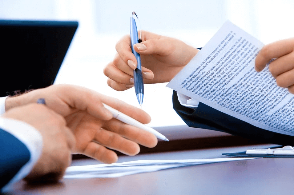 Image of two employees reviewing paperwork, representing the need for WV employers to ensure compliance with company policies.