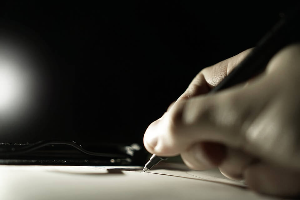 Image of a person with pen in hand writing on a blank piece of paper, representing how documenting your wishes before you die and hiring an attorney who knows West Virginia Intestate Laws will ensure your wishes are carried out.