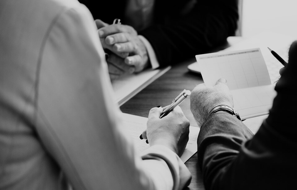 Image of people in suits holding a discussion over paperwork, representing the need to recover a workers’ compensation overpayment and how attorney Steven K. Wellman, can help with workers’ compensation issues.