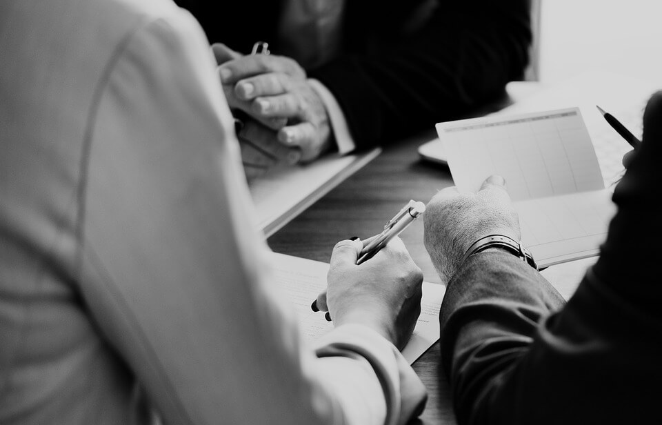 Image of people in suits holding a discussion over paperwork, representing the need to recover a workers’ compensation overpayment and how attorney Steven K. Wellman, can help with workers’ compensation issues.