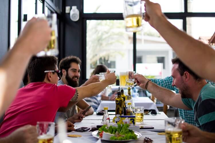 Image of a group of men at a restaurant, representing the restaurant COVID solutions that will persist as customers return to safe dining indoors.