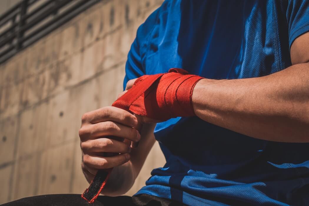 Image of a man wrapping a bandage around his wrist as if in pain, representing how an employer defending appeals under the WV workers’ compensation statute of limitations needs experienced counsel such as Steven K. Wellman at Jenkins Fenstermaker, PLLC.