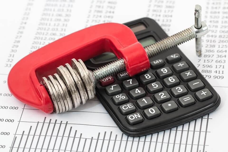 An image of financial paperwork and a calculator with a small vice holding coins, representing the need for personal asset protection and the benefits of DAP trusts for CPAs and other accountants.