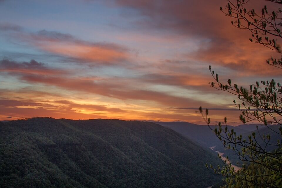 Image of a sunset over forested mountains, representing the peaceful balance sought by legislators who proposed the WV religious freedom law and how the attorneys at Jenkins Fenstermaker, PLLC, can help you determine your rights and responsibilities under the current state of the law.