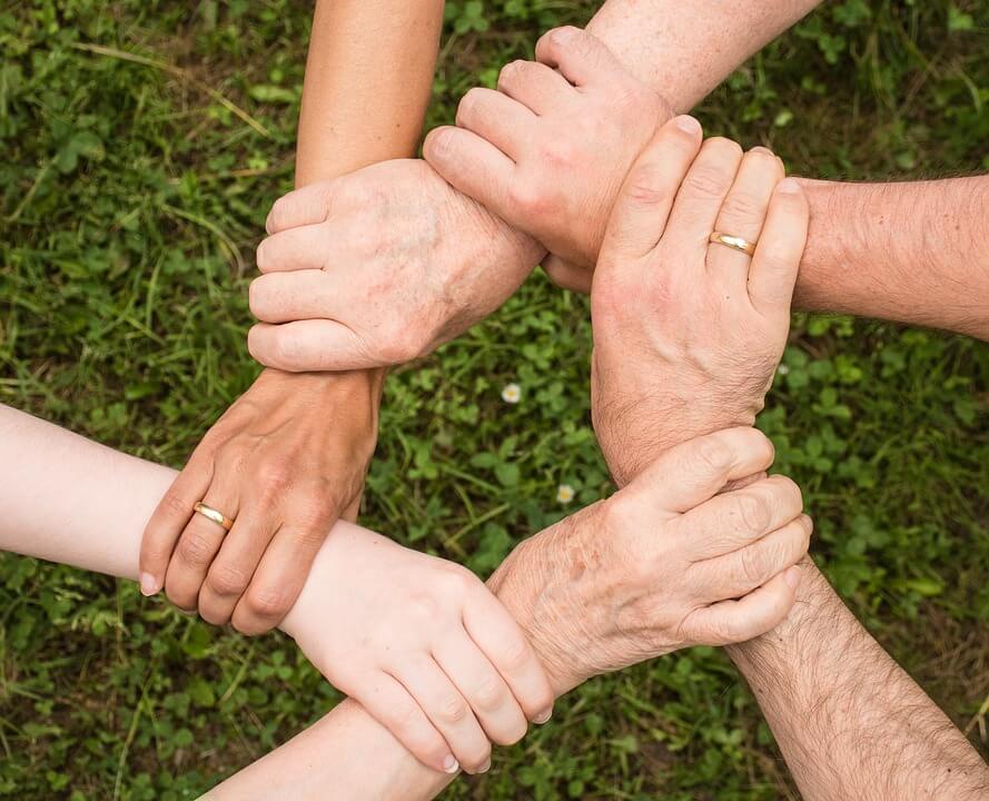 An image of an interlocked circle of hands, representing the need for communicating your estate plan to help your family understand your true wishes and prevent disputes during the settlement of your estate.