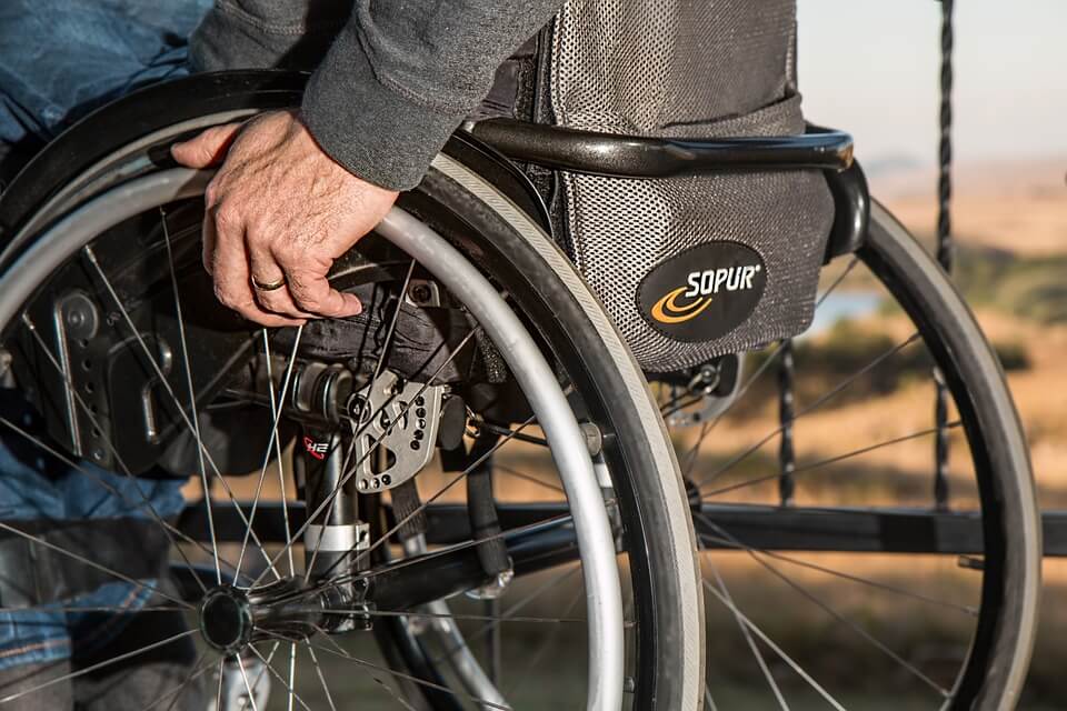 Image of a man in a wheelchair with his hand on the wheel, representing the difficulty of navigating the Social Security Administration maze, and why it’s important to discuss Social Security disability benefits with your estate planning attorney in WV, KY, or OH.